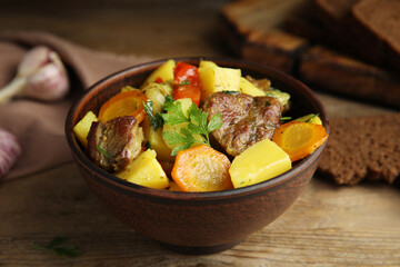 Tasty cooked dish with potatoes in earthenware served on wooden table