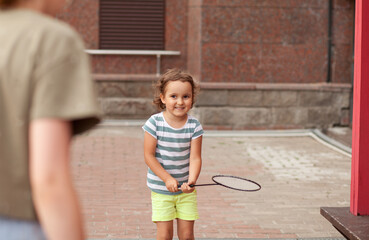 Little adorable girl playing badminton active outdoor game