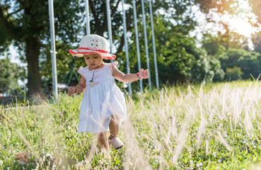 Little girl walking on meadow with sunset.