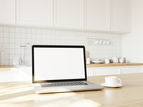Bright morning sun shines through window on table with laptop and cup of coffee. Kitchen background.