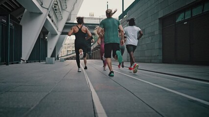 Rear view athletes runners train in the stadium. Young team of man and woman in sportswear and shoes. Like-minded club