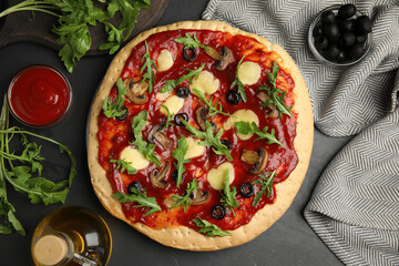 Pita pizza with cheese, olives, mushrooms and arugula on black table, flat lay