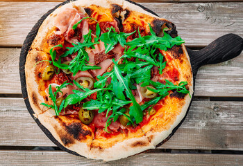 neapolitan Pizza with Mozzarella cheese, ham, bacon, tomato, Spices and jalapeno in cafe outdoor