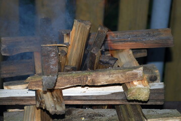 Pine firewood is stacked in a square for a fire. Several pieces of wood are stacked in a square fire tower in the middle of the tower, other firewood is stacked vertically.