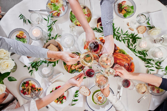 Friends, family clink glasses at the festive table. Cheers. Top view. Celebrating the new year 2022. High quality photo