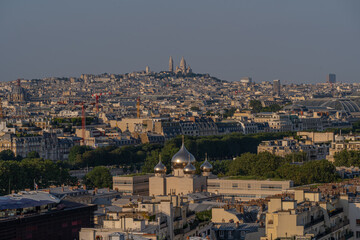 Fototapeta na wymiar Paris, France - 07 22 2021: Eiffel Tower: View of Cathedral of the Holy Trinity and Montmartre district at sunset in Paris