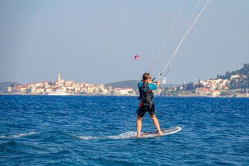 CLOSE UP: Athletic woman foilsurfs near the old town of Korcula on a sunny day