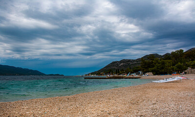 Fototapeta na wymiar Dark stormy clouds gather above a popular windsurfing beach in Peljesac, Croatia
