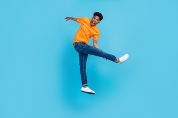 Full body photo of funny brunet millennial guy jump yell wear orange t-shirt jeans isolated on blue...