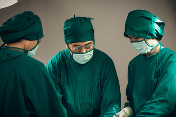 Fototapeta na wymiar Asian Medical Team Performing Surgical Operation in Modern Operating Room. Doctors and Nurse in green uniform concentrate working in the hospital