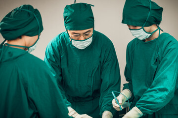 Fototapeta na wymiar Asian Medical Team Performing Surgical Operation in Modern Operating Room. Doctors and Nurse in green uniform concentrate working in the hospital