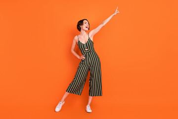 Full size photo of funny brunette young lady dance wear overall sneakers isolated on orange background