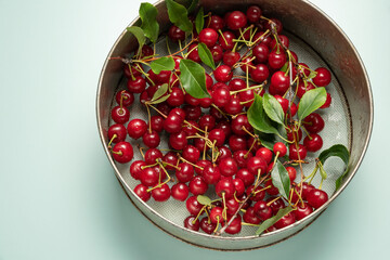 cherries in a steel sieve on an azure background.Clean, washed berries with water drops.