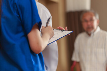 Close up Nurse hand writing the check up result from the doctor into her clipboard. Asian Doctor nurse and parent talking ing patient room