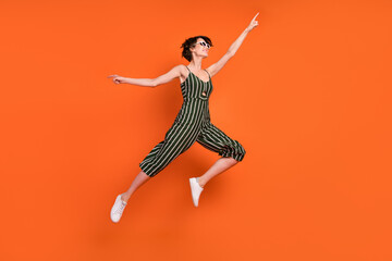 Fototapeta na wymiar Full body profile side photo of young girl happy positive smile jump up energetic isolated over orange color background