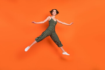 Fototapeta na wymiar Full size profile side photo of young excited girl happy positive smile jumper split sporty isolated over orange color background