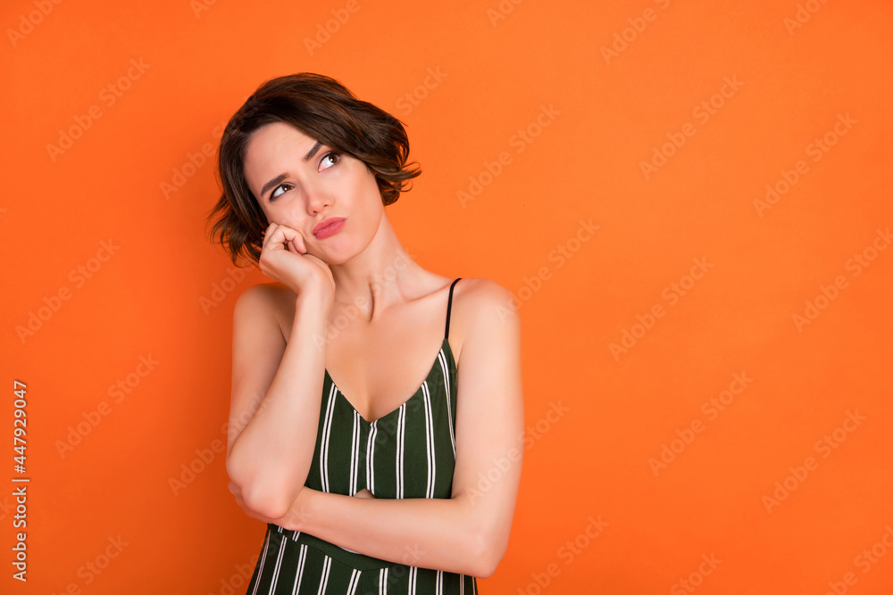 Poster Photo of young girl hand touch cheek bored annoyed think idea plan look empty space isolated over orange color background