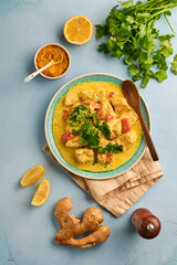Chicken tikka masala. Traditional of indian cuisine curry and ingredients on dark background. Curry, lime, ginger, cilantro, chili, rice, herbs and spices. Top view with copy space.