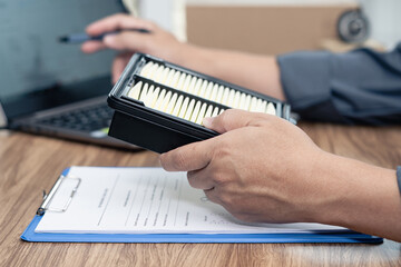 Close up hand technician holding air filter of engine car and use computer laptop check the correctness of the spare parts in car service center office