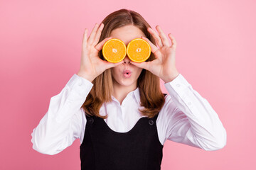 Photo of sweet impressed school girl wear black white uniform holding two orange slices close eyes...