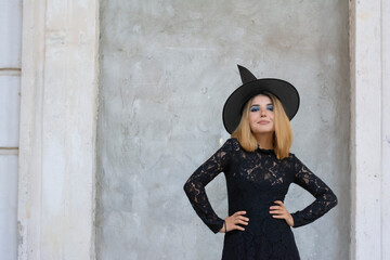 Young witch in black dress and cap halloween all saints day free space for text