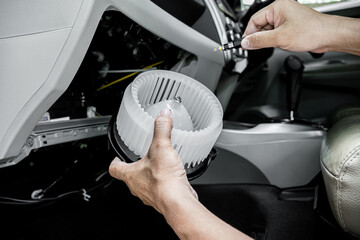 Technician in the service center install and maintenance blower air of car and use screwdriver...