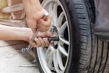 Home service car concept : A man repairing action lock bolt of car wheel for check the car's drive...