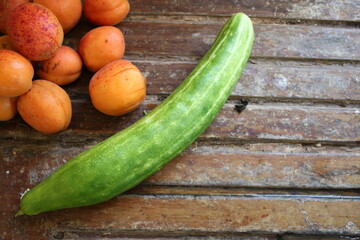 Close up of fresh apricot ripe juicy fruits from English garden orchard in Norfolk countryside in Summer on kitchen sink rustic wood draining board with cucumber for vegan raw diet meal