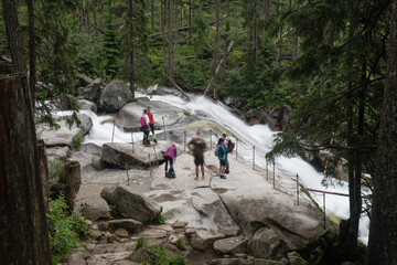 Tourists admiring beauty of Cold water waterfalls in High Tatra mountains, Slovakia