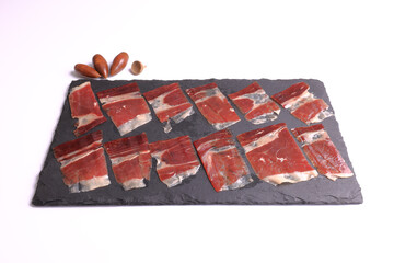 Portion of acorn-fed Iberian ham 100% Dehesa de Extremadura, on a slate plate decorated with acorns...