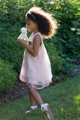 Vertical view of beautiful little girl in pink dress holding and kissing a small stuffed lamb toy, Quebec City, Quebec, Canada © Anne Richard