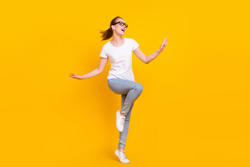 Full length photo of cheerful young funky woman look empty space smile isolated on yellow color background