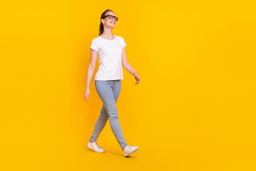 Full size profile side photo of young woman happy positive smile go walk step isolated over yellow color background