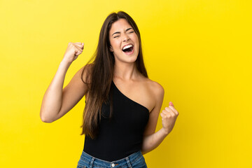 Young Brazilian woman isolated on yellow background celebrating a victory