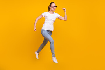Full length photo of young happy cheerful woman jump up run empty space isolated on yellow color background