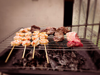 Cocinando con carbon y fuego unos langostinos y carne