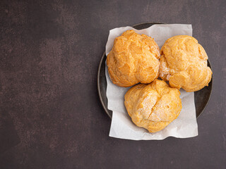 Top view of choux cream on a plate placed on a dark brown background. Space for text. Space for text. Concept of relaxation