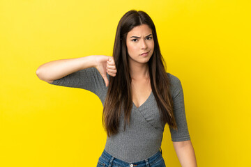 Young Brazilian woman isolated on yellow background showing thumb down with negative expression