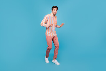 Fototapeta na wymiar Full length photo of charming young happy man amazed attractive man walk isolated on pastel blue color background