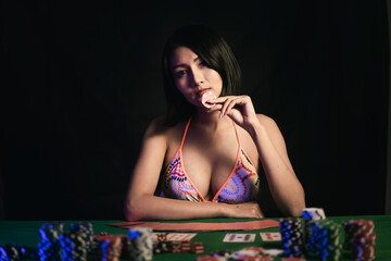 sexy women wearing bikini holding poker chips at the poker table in casino