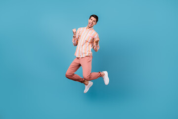 Full size photo of young man jump happy positive smile rejoice victory success isolated over blue...