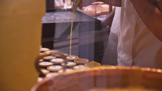 pastry chef behind the counter makes and fills traditional Portuguese pastel de nata pastries with custard