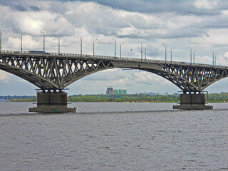 Obraz premium Bridge span over the river with a view of trees and high-rise buildings