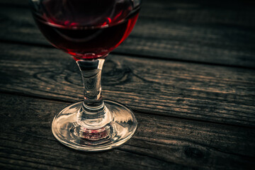 Glass of red wine on an old wooden table. Close up view