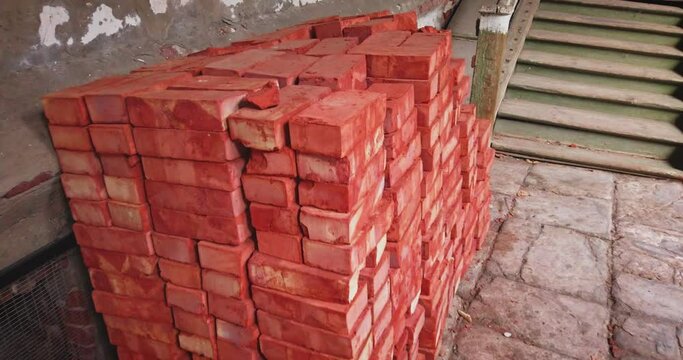 Stacks of red bricks for construction purpose in the old house yard.