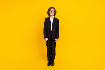 Photo of cheerful positive boy beaming smile wear eyewear black uniform isolated yellow color...