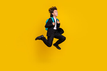 Fototapeta na wymiar Profile photo of carefree small boy jump run wear rucksack black uniform isolated yellow color background