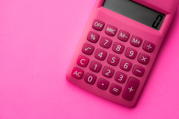 Close up of a pink modern calculator with white numbers on a pink surface 