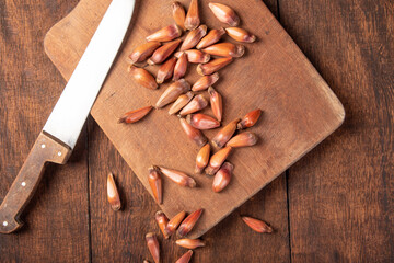 Pinhão, pinion, pine fruit, Brazilian Araucaria tree, on rustic wood with a knife, top view.