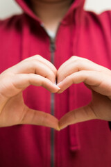 Woman wearing red jacket making  a heart with her hands 